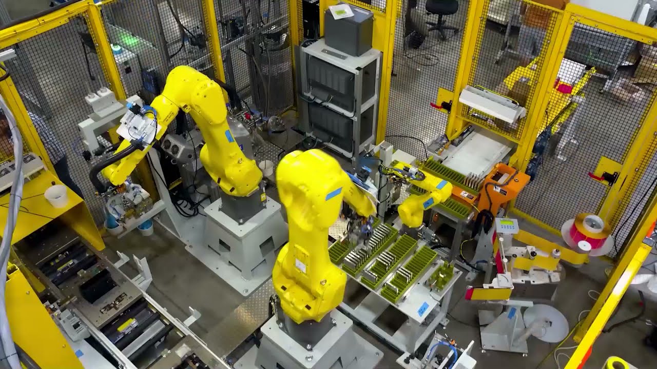 Yellow FANUC robotic arms in an automated industrial manufacturing cell